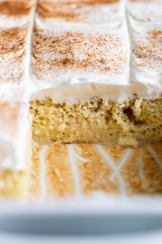 View into a pan of Mexican tres leches cake. A couple slices are missing from the front. 