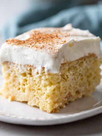 A slice of tres leches cake on a white plate.