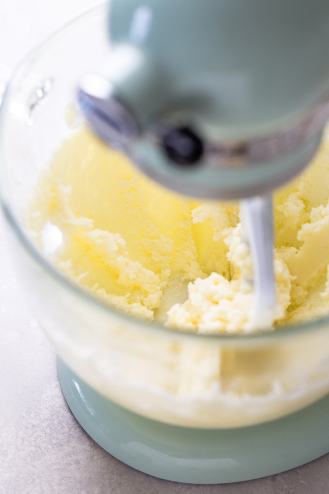 Process shot showing butter and sugar being creamed together in a stand mixer.