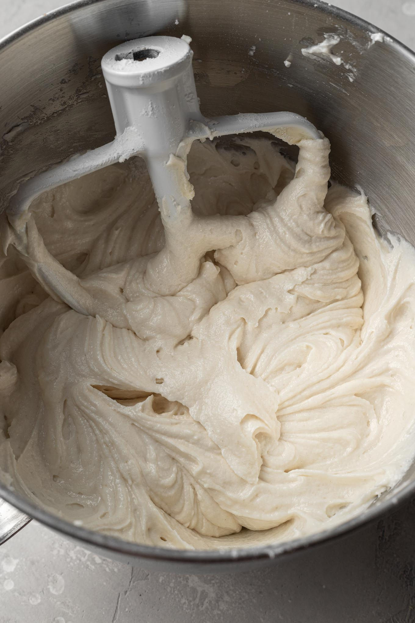 An overhead view of white cake batter in a stand mixer.