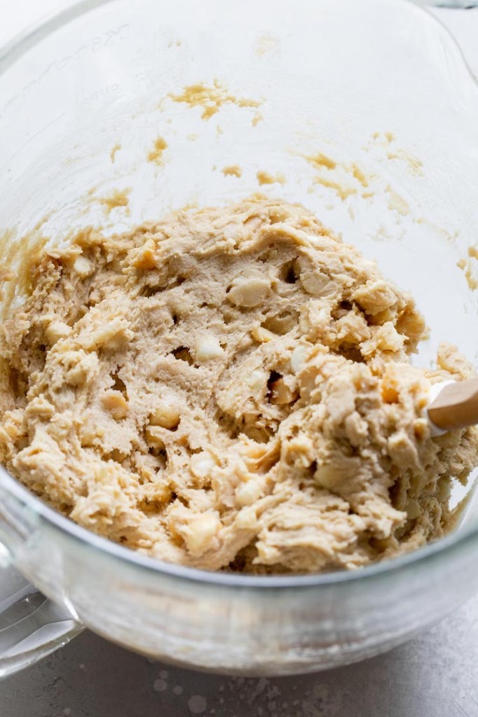 The finished white chocolate macadamia nut cookie dough mixed together in a glass mixing bowl.