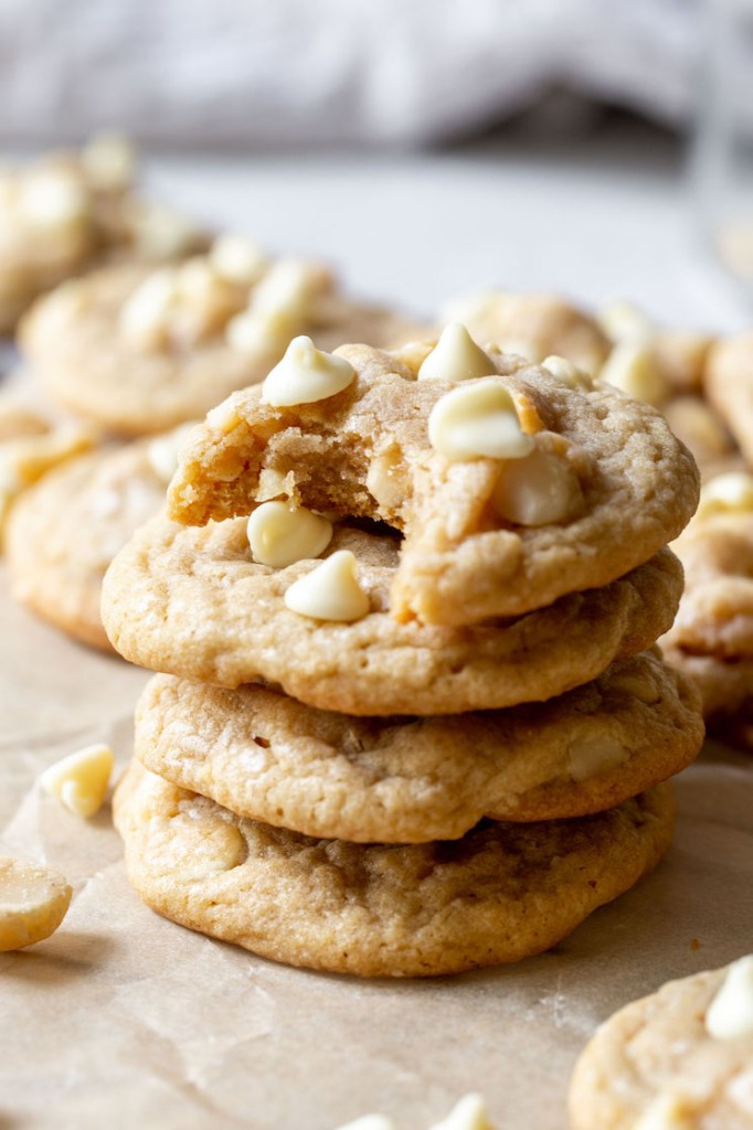 A stack of white chocolate macadamia nut cookies surrounded by more cookies.