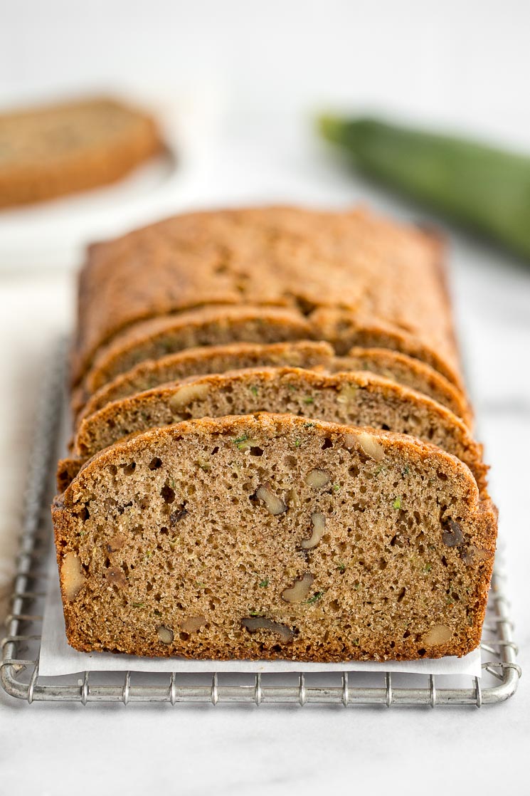 A sliced zucchini bread sitting on top of an antique safety grater. 