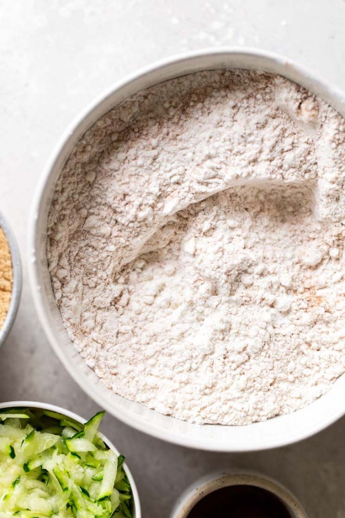 An overhead view of the dry ingredients for zucchini bread muffins in a mixing bowl.